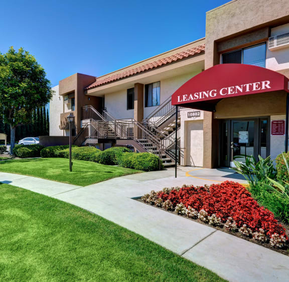 the leasing center of the gems leasing center building with grass and flowers and a sign