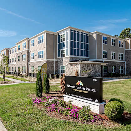 a large building with a sign in front of it on a lawn