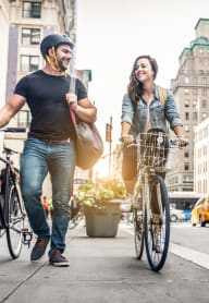 a couple walking their bikes down a city street