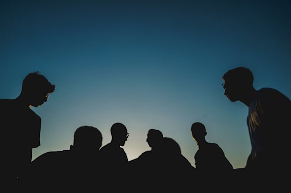 a group of men standing in silhouette against a blue sky