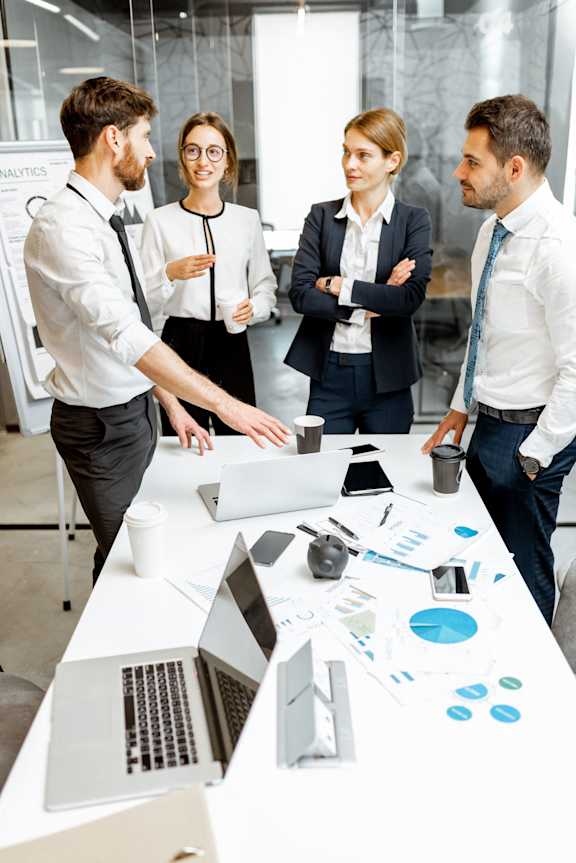 Four business people having a meeting around a table with laptops and papers.