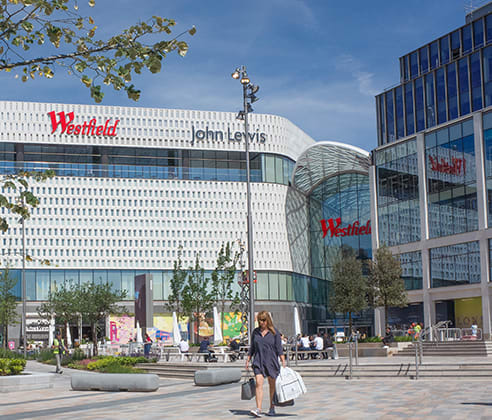 people sitting on the grass in front of a building with a clock tower