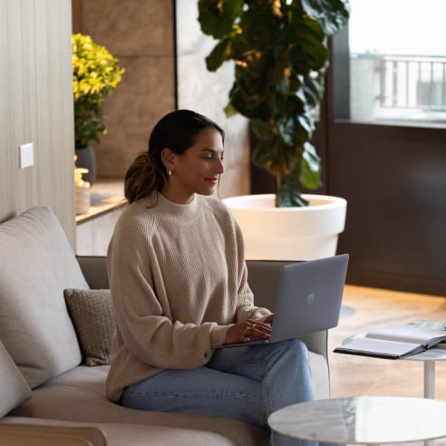 a woman sitting on a couch using a laptop computer