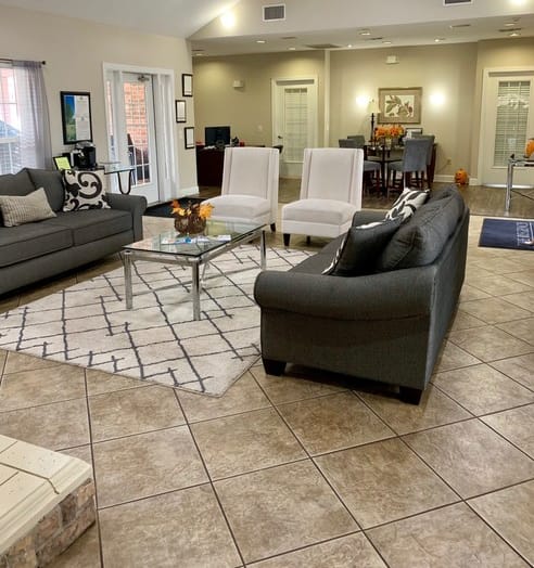 A living room with a grey couch, a black chair, and a coffee table. at The Regency, Manassas, VA