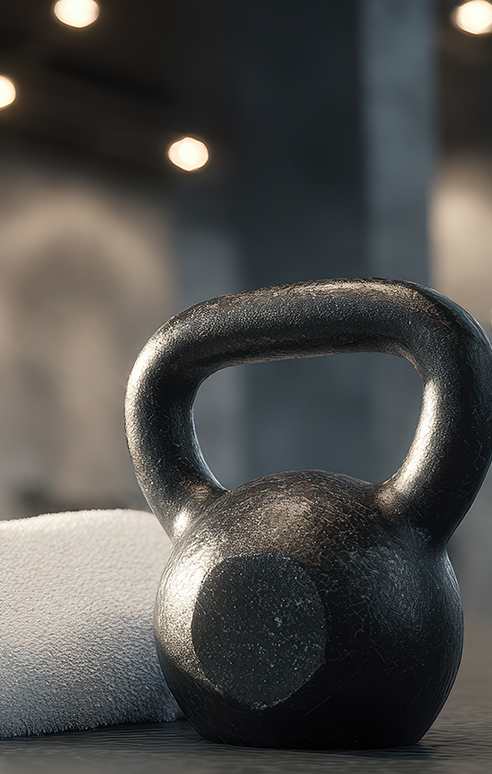 A black kettlebell rests on a white towel on a wooden surface.