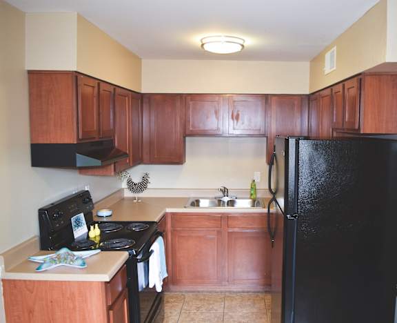 a kitchen with wooden cabinets and a black refrigerator