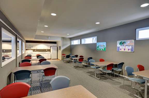 A room with tables and chairs and a wall with posters on it.