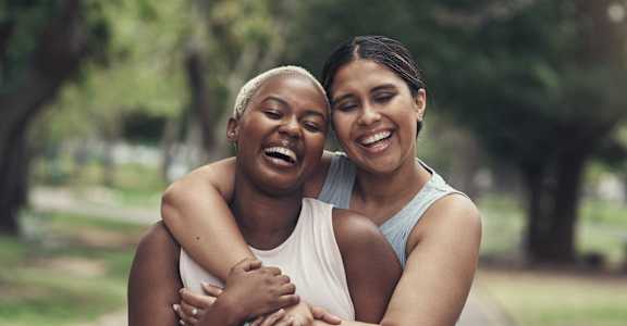 two women hugging each other in a park