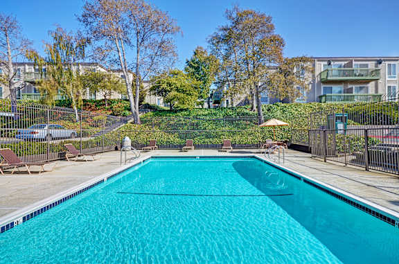 A swimming pool surrounded by a fence and trees.