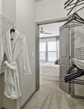 a walk in closet with a white robe hanging on the wall and a closet door
