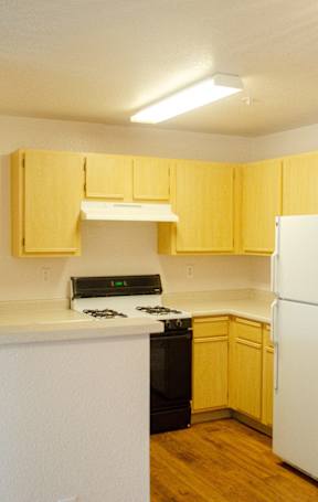 A kitchen with yellow cabinets and a black stove top oven at Arrowhead Ridge Apartments, Rio Rancho, NM, 87124