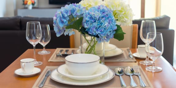 a dining table with a vase of blue and white hydrangeas