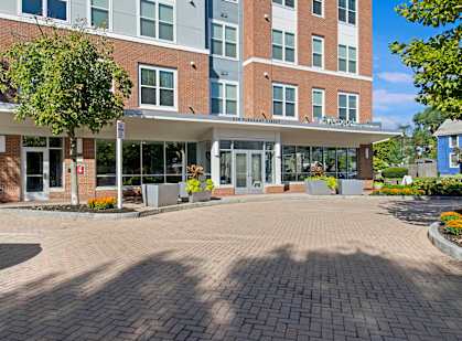 A large brick building with a glass entrance and a tree in front.