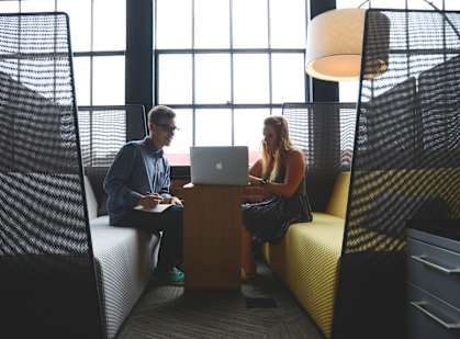 a man and woman sitting on couches looking at a laptop computer