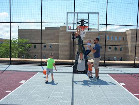 a man in a blue shirt and khaki shorts is dunking a basketball on a basketball