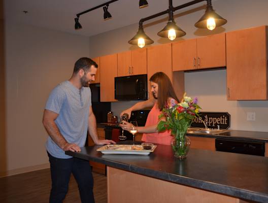 a man and a woman standing in a kitchen preparing food