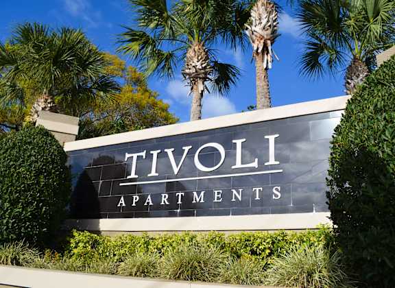 a sign for tivoli apartments in front of palm trees at Tivoli Apartments of Orlando, Oviedo, 32765