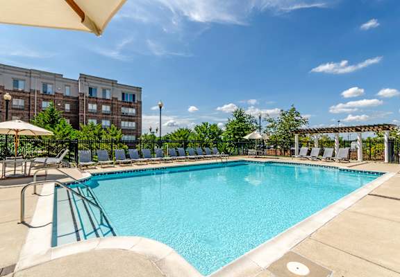 A large swimming pool surrounded by lounge chairs and umbrellas.