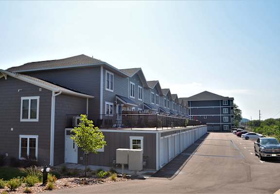 a row of townhomes with cars parked on the side of the road