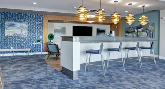 A modern office waiting area with a white reception desk and blue chairs.