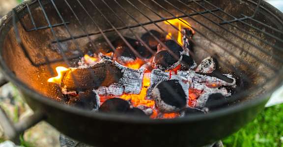 A grill with burning coals and food cooking on it.