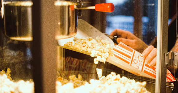 a person scooping popcorn out of a box in a popcorn machine