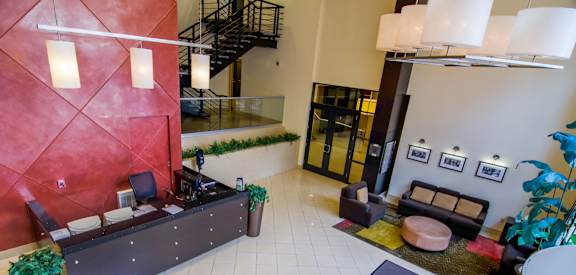 A reception area with a red wall and a black couch.
