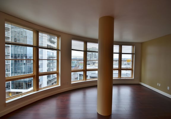 an empty living room with large windows and a column