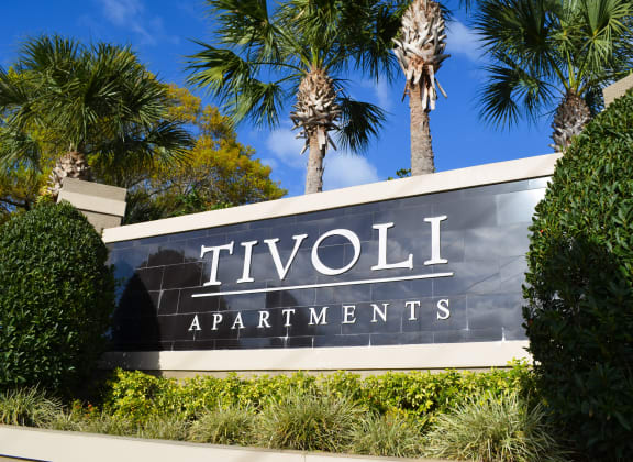 a sign for tivoli apartments in front of palm trees