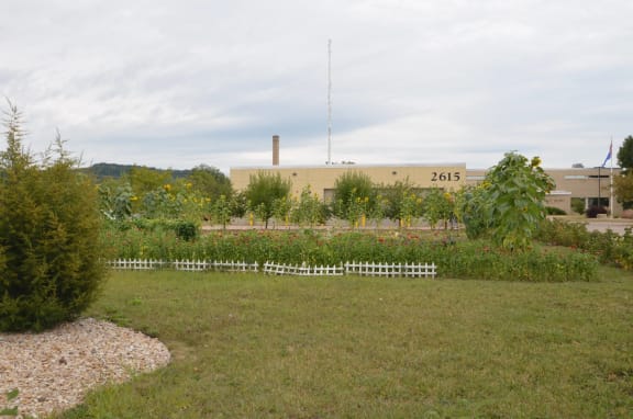 a garden with a white fence in front of a building