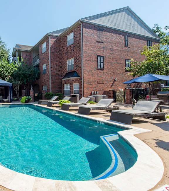 A large outdoor swimming pool surrounded by lounge chairs and umbrellas.
