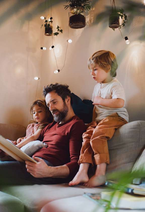 A family of three is sitting on a couch together.