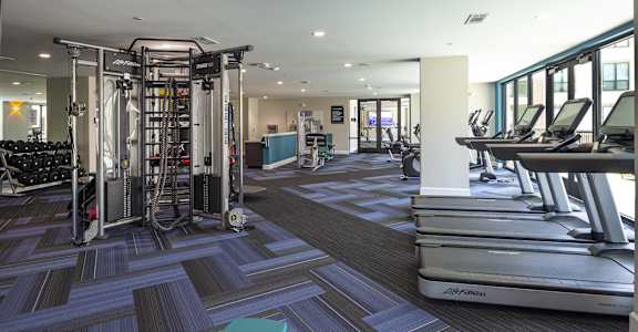 a gym with cardio machines and weights on the floor