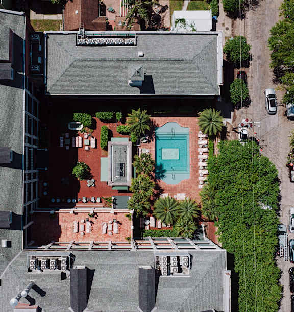 A modern building with a grey roof and a pool in the middle.
