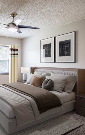 A bedroom with a large bed, a ceiling fan, and two lamps.