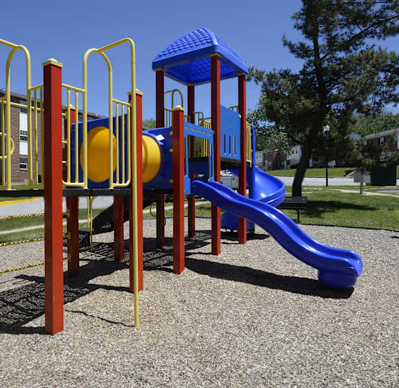 A playground with a blue slide and yellow and red play structures.