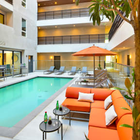 a swimming pool with orange couches and a table with a bottle of wine