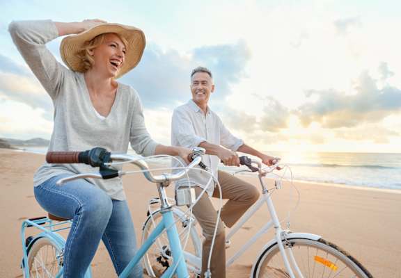 a man and woman riding bikes on the beach