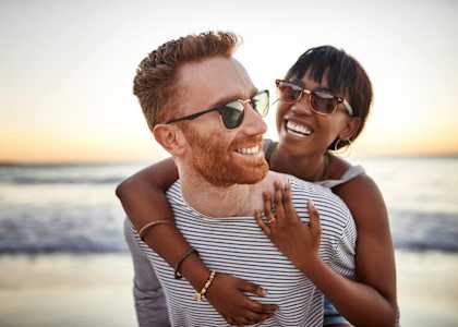 a man and a woman hugging on the beach at The Port at East Beach Apartments and Marina, Virginia