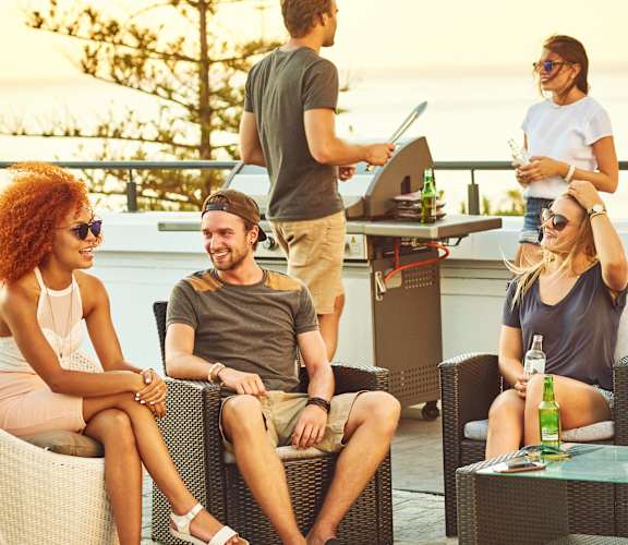 A group of people are sitting and standing around a table on a patio.