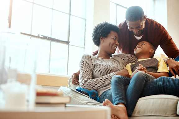 A family of three is sitting on a couch together at The Dawson Cartersville Apartments, Cartersville, GA, 30121
