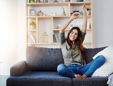 a woman sitting on a couch with her arms in the air