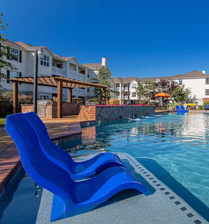 A swimming pool with blue loungers and a clear sky.