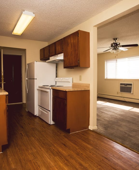 an empty kitchen with wooden floors and a white refrigerator