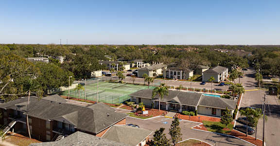 A tennis court is surrounded by houses.
