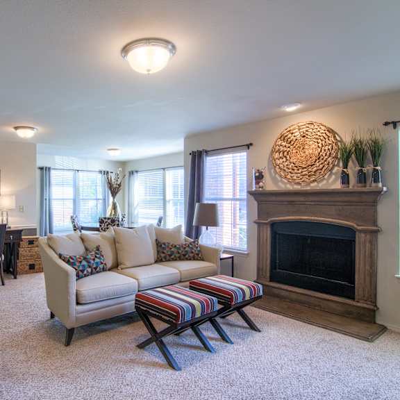 A living room with a couch, desk and chair, and a fireplace at Villas at Preston Lakes Apartment Homes. 
