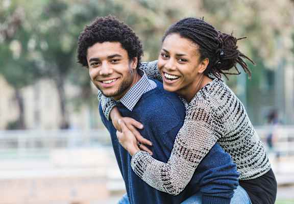 A man and a woman are hugging each other in a park.
