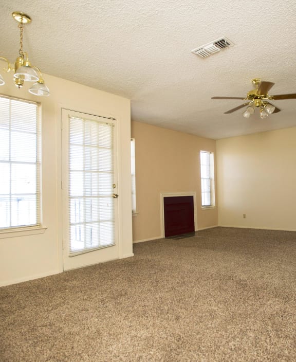 an empty living room with a ceiling fan and windows