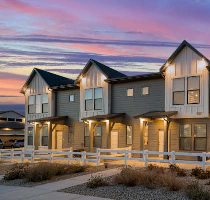 a row of houses with lights on at sunset