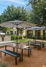 a picnic area with benches and umbrellas in a park